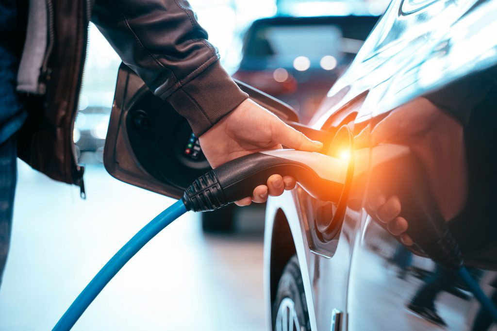 A man connects a charging cable to his electric car, powering it up for the journey ahead